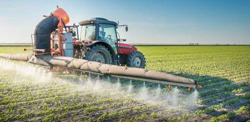 Tractor spraying pesticides on crops.