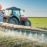 Tractor spraying pesticides on crops.