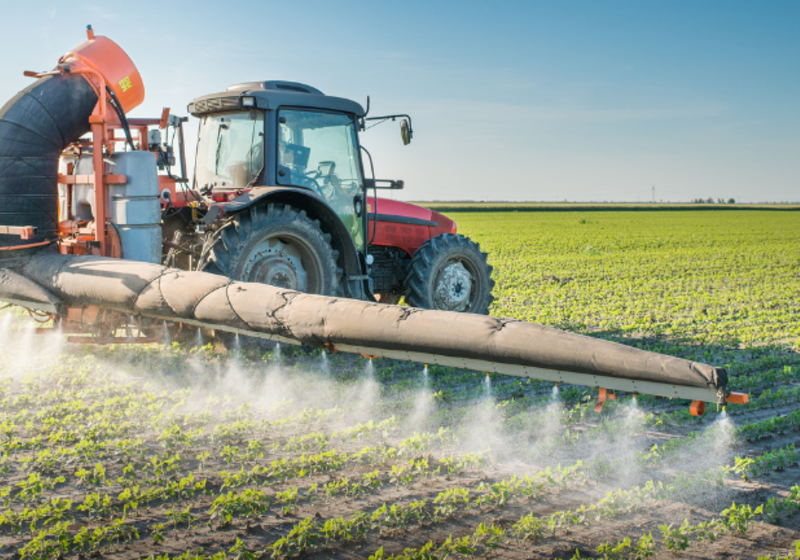 Tractor spraying pesticides on crops.
